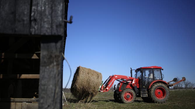 Tractor lifting bale of hay.